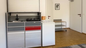 A compact kitchen with a built-in stove, a coffee maker, and a small sink. - BoardingHouse - Studios & Apartments (Kassel)