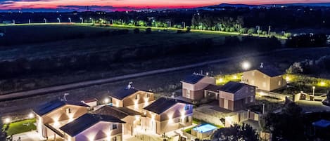 Un complejo residencial con varias casas, una piscina y un camino de entrada bien iluminado.