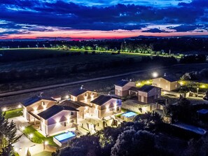 Un complesso residenziale con diverse case, una piscina e un vialetto ben illuminato.