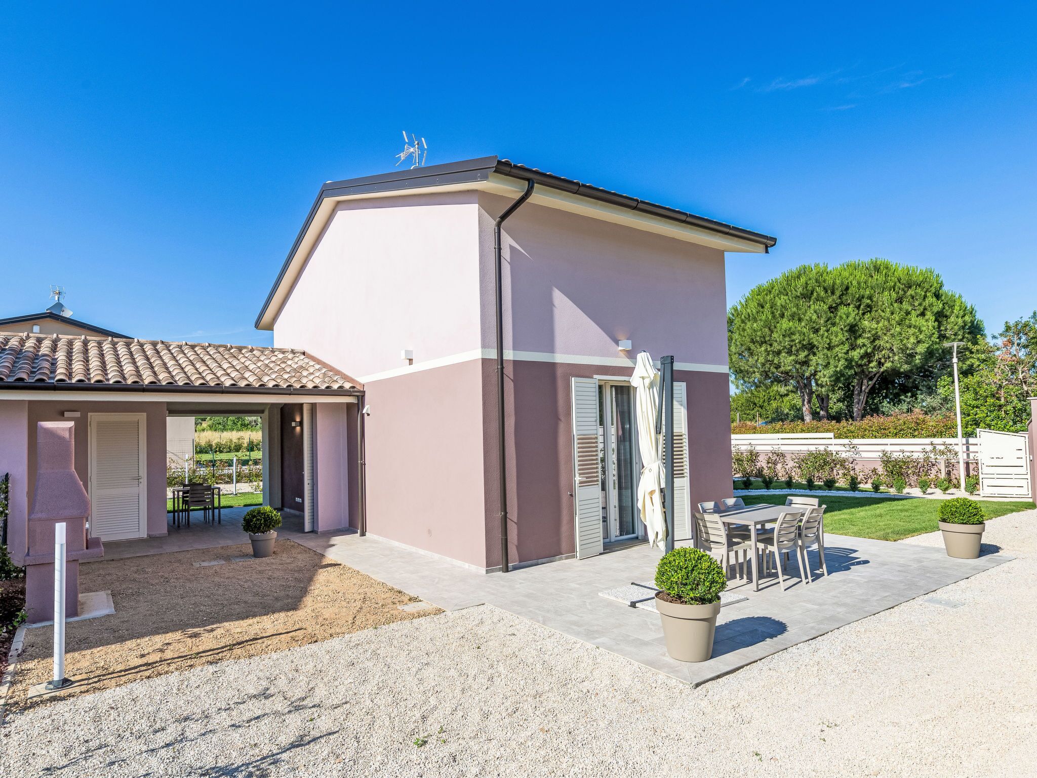 Un bâtiment à deux étages doté d’un patio couvert, d’un petit jardin et d’une porte bien visible.