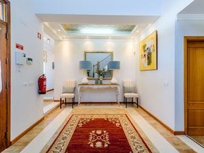 A hallway with a red patterned rug, a console table with two lamps, a mirror, and a fire extinguisher. - Endless Summer Luxury Villa by Interhome (Almancil)