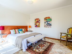 A hotel room with a bed, a bench, a chair, a lamp, and two wall art pieces. - Endless Summer Luxury Villa by Interhome (Almancil)