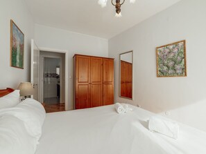 Ein Hotelzimmer mit Bett, einem Holzschrank, einem Spiegel und einem Gemälde an der Wand.