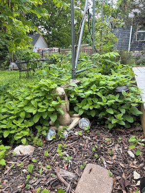 A garden with a stone sculpture, mulch, and various plants.