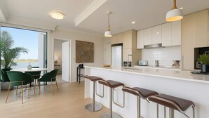 A modern kitchen with a white countertop, stainless steel appliances, and bar stools. - Luxury Lakeview 3BR Escape (Robina)