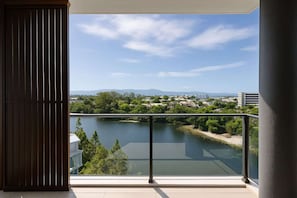A balcony with a view of a river, greenery, and distant buildings. - Luxury Lakeview 3BR Escape (Robina)