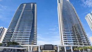 Two high-rise buildings with a modern architectural design, featuring numerous balconies and a clear sky in the background. - L54 Sky Ocean View Apt Heated Pool (Surfers Paradise)