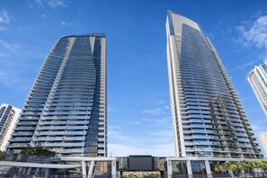 Two high-rise buildings with a modern architectural design, featuring numerous balconies and a clear sky in the background. - L54 Sky Ocean View Apt Heated Pool (Surfers Paradise)