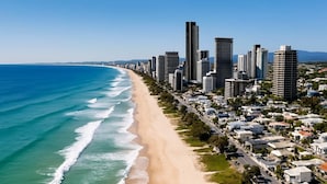 A coastal cityscape with a beachfront, high-rise buildings, and a road parallel to the beach. - L54 Sky Ocean View Apt Heated Pool (Surfers Paradise)