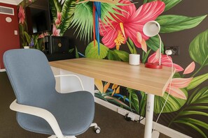 A room with a desk, chair, TV, and a floral wall mural. - L22 Ocean View 2 Beds Wi-Fi Netflix (Surfers Paradise)