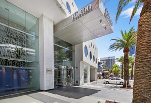 A modern hotel entrance with a glass facade, a prominent 'Hilton' sign, and palm trees in the foreground. - H Residence L19 Ocean view 2BR (Surfers Paradise)
