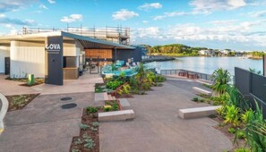 A modern building with a pool, outdoor seating, and a waterfront view. - Waterview Hope Island House (Hope Island)