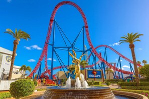 A theme park with roller coasters, a fountain, and a building with a sign. - Waterview Hope Island House (Hope Island)