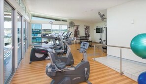 A gym with cardio machines, a green exercise ball, and a large window with a view. - Waterview Hope Island House (Hope Island)