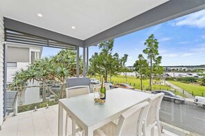 A balcony with a table, chairs, and a bottle of champagne. - Waterview Hope Island House (Hope Island)