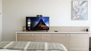 Ein Hotelzimmer mit einem Bett, einem Fernseher auf einem Schrank, einer Kommode und einem gerahmten Bild an der Wand.