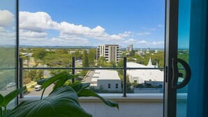 A balcony with a view of a cityscape, including buildings and greenery. - Surfers 1BR Retreat: Pool, Spa, Gym & Fast Wi-Fi (Surfers Paradise)