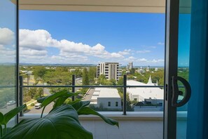 A balcony with a view of a cityscape, including buildings and greenery. - Surfers 1BR Retreat: Pool, Spa, Gym & Fast Wi-Fi (Surfers Paradise)