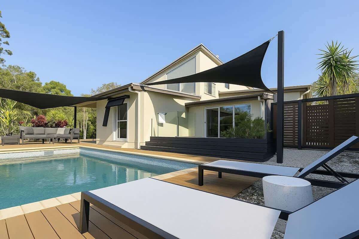Una casa moderna con piscina, mobiliario de exterior y zona sombreada.