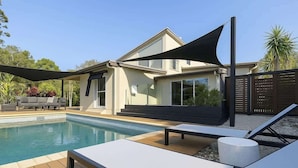 A modern house with a swimming pool, outdoor seating, and a shaded area. - Dreamworld Home with Pool, BBQ, WI-FI and Backyard (Oxenford)