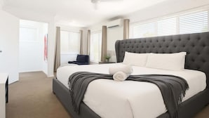 A bedroom with a large bed, a ceiling fan, and a window with blinds. - Dreamworld Home with Pool, BBQ, WI-FI and Backyard (Oxenford)