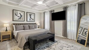 Camera da letto con un letto, comodini, una panca, una ventola a soffitto, una TV e tende.