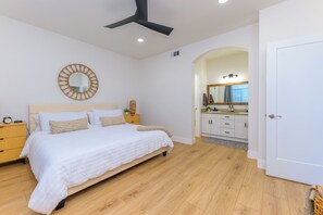 Une chambre à coucher avec un lit, une table de chevet et un ventilateur de plafond.
