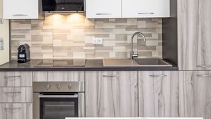 Una cucina moderna con forno integrato, elettrodomestici in acciaio inossidabile, un lavello a due vasche e un forno a microonde.