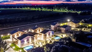Una zona residenziale con diverse case, ciascuna dotata di piscina e illuminazione esterna.