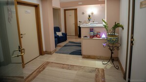 A hotel lobby with a reception desk, a blue armchair, a potted plant, and a tiled floor. - Luxury b&b Villa Bellini: residential oasis 5 minutes from downtown (Catania)
