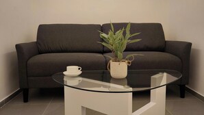 A modern living room with a dark grey sofa, a glass coffee table with a white mug and a potted plant. - Luxury b&b Villa Bellini: residential oasis 5 minutes from downtown (Catania)