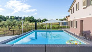 Ein Swimmingpool mit Pergola, Sitzgelegenheiten im Freien und Blick auf die umliegende Landschaft.