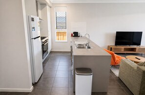 A modern kitchen with a built-in oven, a sink, and a window with a view. - Solara Retreat | Modern 4BR Home with Backyard (Warner)