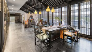A spacious dining area with a long table, chairs, and hanging pendant lights. - Gongxili - Pujian Hotel (Kunming)