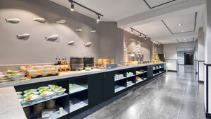 A modern hotel kitchen with a long counter, various food stations, and a wall decorated with fish shapes. - Gongxili - Pujian Hotel (Kunming)