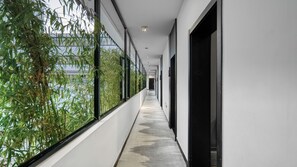A corridor with a concrete floor, large windows on one side, and a door on the other. - Gongxili - Pujian Hotel (Kunming)