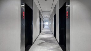 A long, narrow hallway with black doors on either side, each marked with red text. - Gongxili - Pujian Hotel (Kunming)