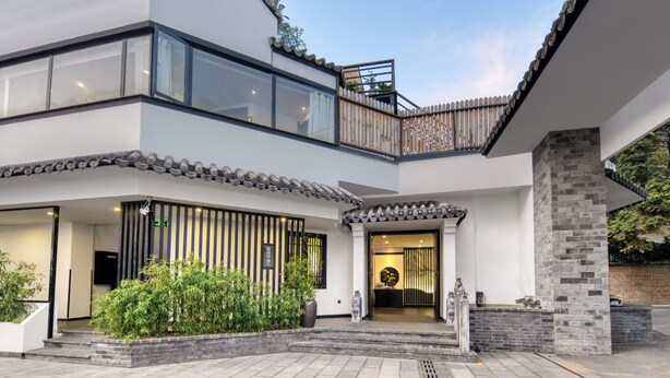 A modern building with a two-story entrance, a balcony, and a traditional tiled roof. - Gongxili - Pujian Hotel (Kunming)