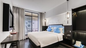 A hotel room with a bed, a desk, a TV, and a window with curtains. - Gongxili - Pujian Hotel (Kunming)