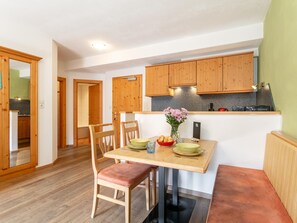 Eine moderne Küche mit Holzschränken, einem Esstisch mit Stühlen und einer kleinen Arbeitsfläche mit Geräten.