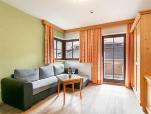 Ein Wohnzimmer mit einer Couch, einem kleinen Tisch und einem Fenster mit Vorhängen.