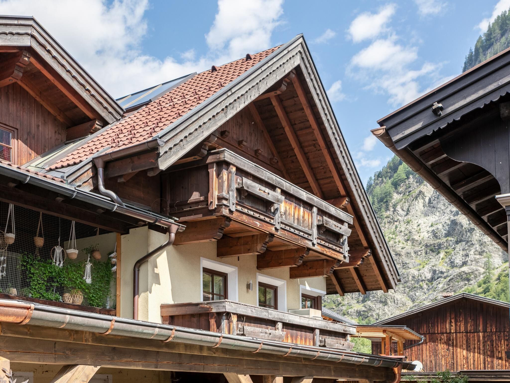A traditional wooden chalet with a steeply pitched roof, wooden balconies, and a mountainous backdrop.