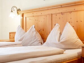 Ein Bett mit weißen Bettwäsche und Kissen, ein hölzernes Kopfende und eine Wandleuchte.