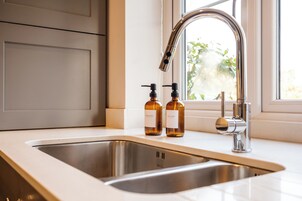 A kitchen with a stainless steel sink, two soap bottles, and a modern faucet.