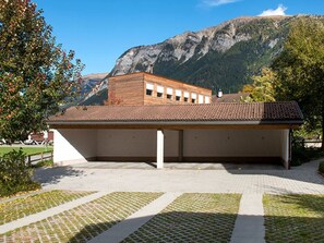 Un edificio con techo de tejas y fachada plana, rodeado de una zona pavimentada con un sendero decorativo.
