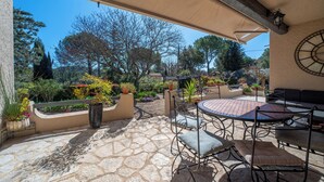 Une terrasse extérieure avec un sol en pierre, des meubles en métal et des plantes en pot.