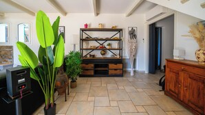 Un vaste espace de vie agrémenté d’un meuble de rangement en bois pour les appareils multimédias, d’une grande plante en pot et d’une cheminée moderne.