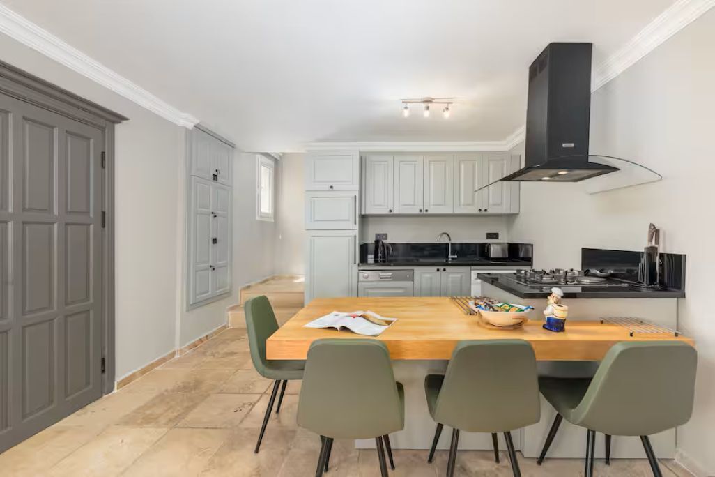 Une cuisine moderne avec des meubles gris, un îlot central en bois et une hotte noire.