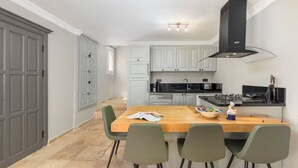 Een moderne keuken met grijze kastjes, een houten eiland en een zwarte afzuigkap.