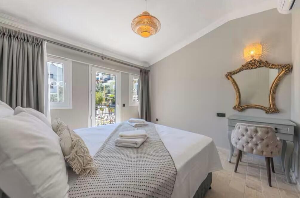 Een slaapkamer met een groot bed, een kaptafel met spiegel en uitzicht door een raam.